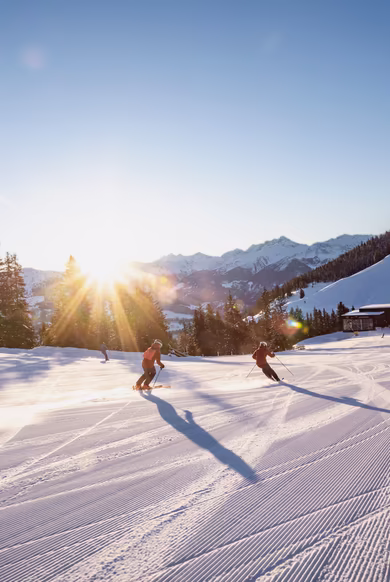 Skifahrer fahren die frisch präparierte Piste im Skigebiet Hochzillertal runter 