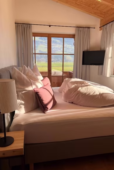 Modernes Schlafzimmer mit Fernseher und einem Balkon mit Ausblick auf das Zillertal