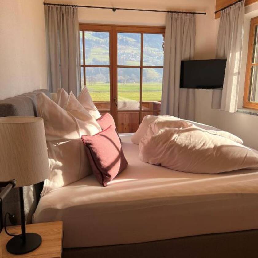 Modernes Schlafzimmer mit Fernseher und einem Balkon mit Ausblick auf das Zillertal